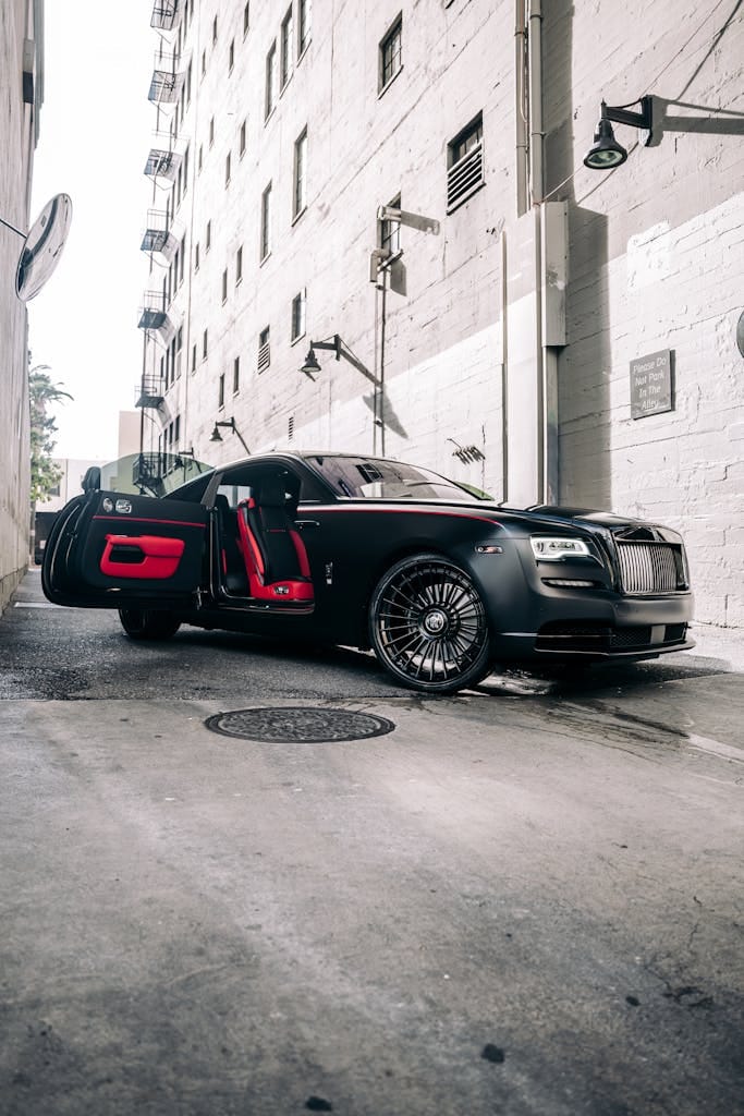 Premium Rolls-Royce Wraith with open coach doors in a modern urban alley, exuding elegance and style.
